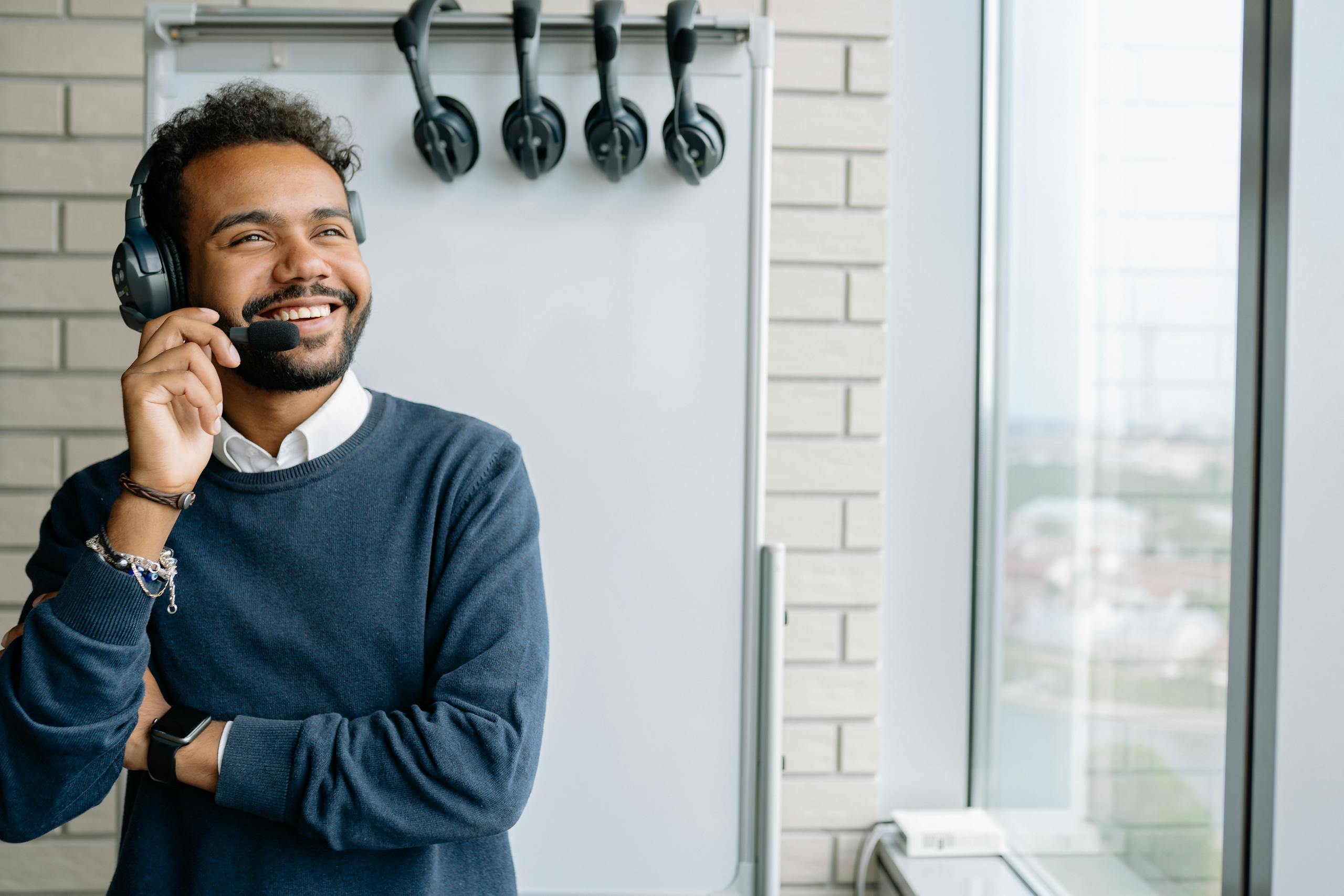 Happy call center agent wearing headphones, smiling in a modern office setting.
